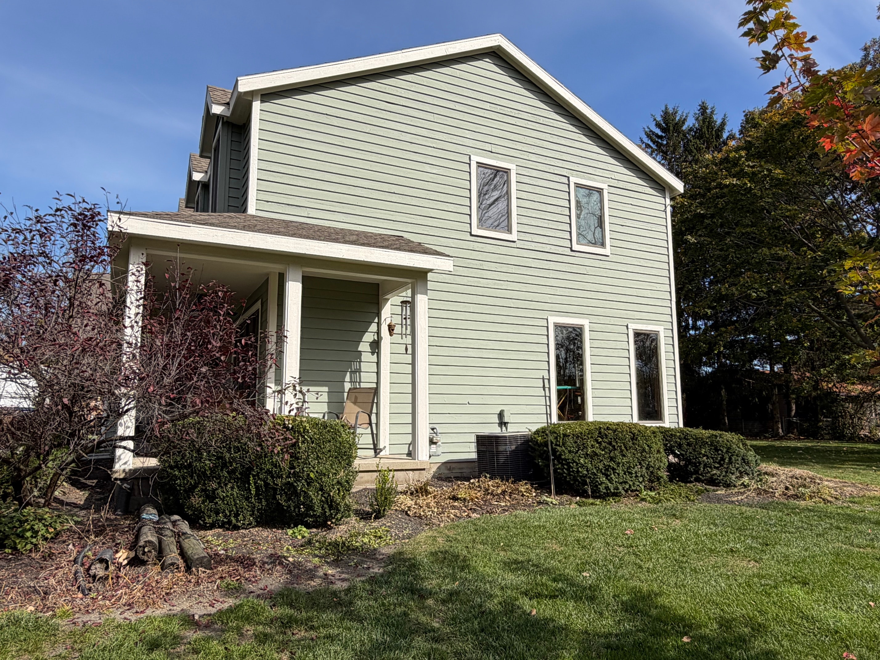 Green two story house covered porch autumn yard